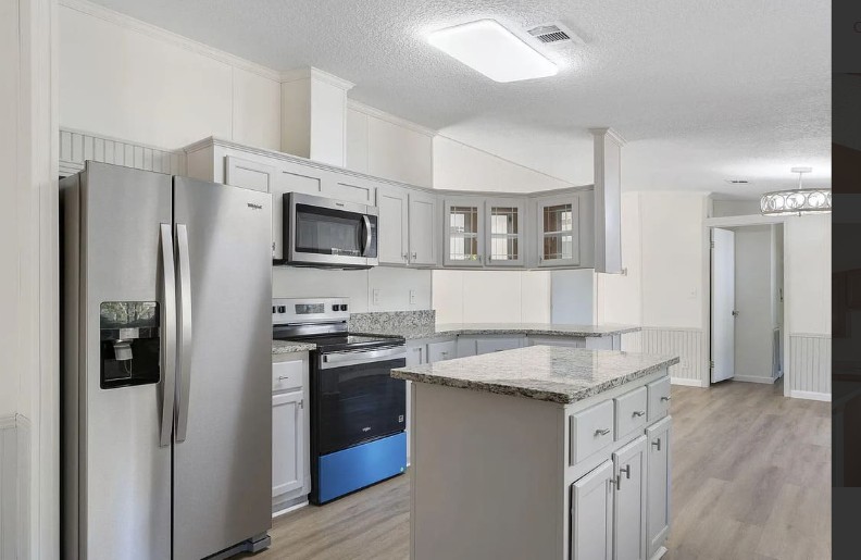 Bright custom kitchen with granite island and stainless appliances